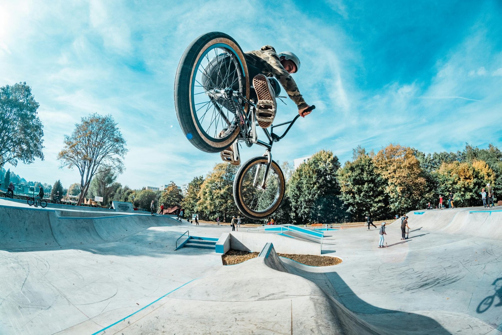 Rider performs a stunning BMX jump at an outdoor skatepark on a clear day.